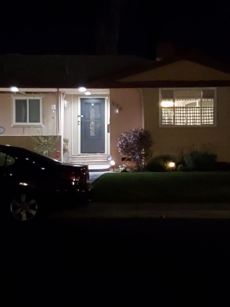 A car parked in front of a house, illuminated by soft night lights, creating a serene nighttime atmosphere.